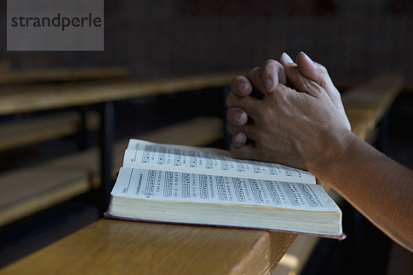 Betende Hände auf einem Gesangbuch in der Kirche