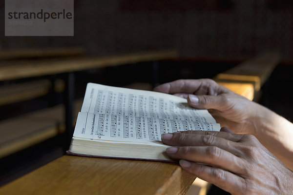 Hände auf einem Gesangbuch in der Kirche