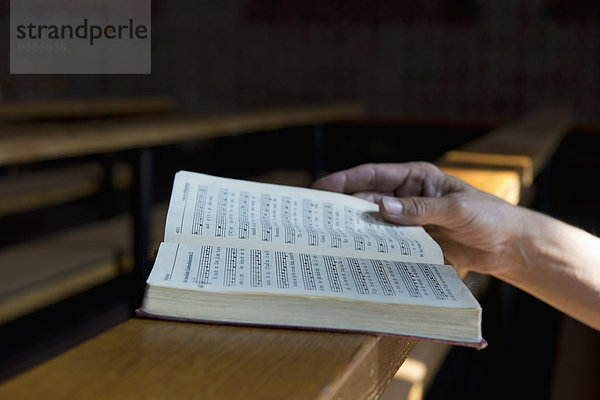 Hand mit Gesangbuch in der Kirche