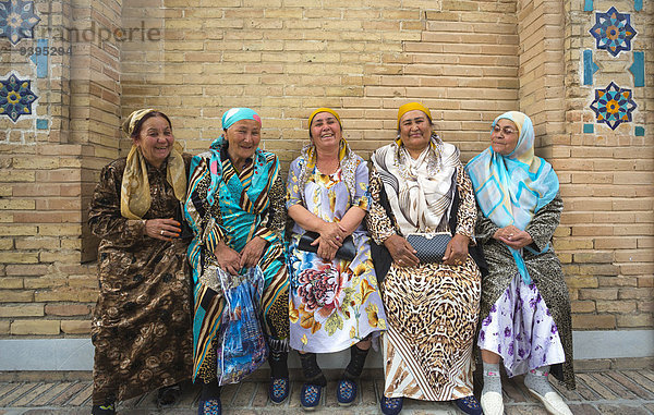 sitzend Frau Tradition lächeln Großstadt bunt Asien Zentralasien Kleid Mausoleum Samarkand Usbekistan