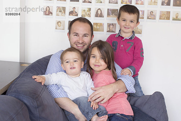 Vater und Kinder sitzen zusammen auf dem Sofa  Porträt