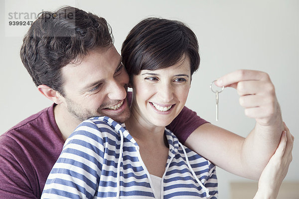 Paar schaut fröhlich auf Hausschlüssel zusammen
