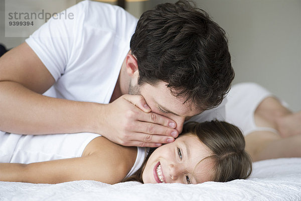 Vater flüstert der jungen Tochter zu.