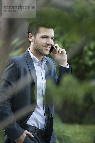 Geschäftsmann im Gespräch mit dem Handy bei einem Spaziergang im Freien