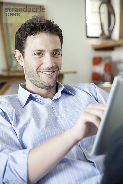 Mann mit digitalem Tablett  lächelnd vor der Kamera