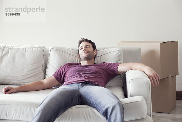 Mann entspannt sich beim Umzug auf dem Sofa