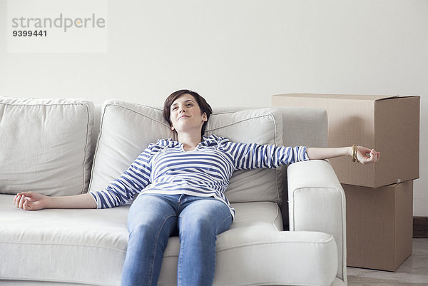 Frau beim Umzug auf dem Sofa liegend