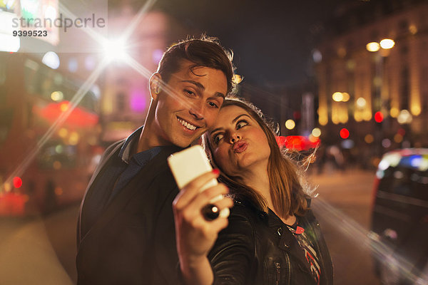 Paar fotografiert zusammen mit dem Handy bei Nacht