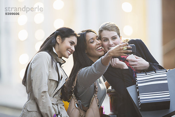 Freunde sprechen Bild mit Handy zusammen in der Stadt Straße
