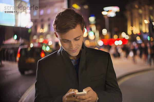 Mann mit Handy in der Stadt bei Nacht