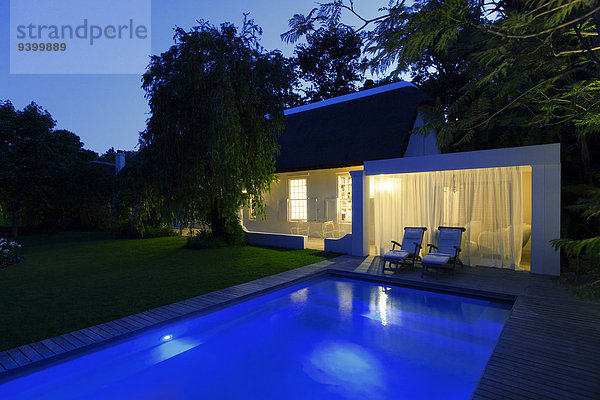 Modernes Haus mit Blick auf das beleuchtete Schwimmbad bei Nacht