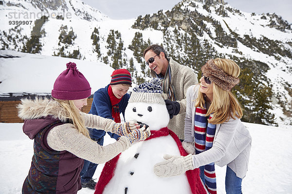 Familie baut gemeinsam einen Schneemann