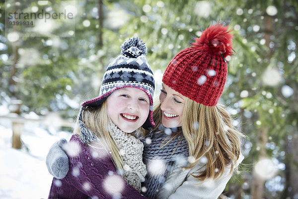 Mutter und Tochter beim Umarmen im Schnee