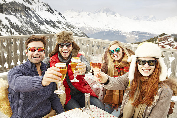 Freunde beim Feiern mit Getränken im Schnee