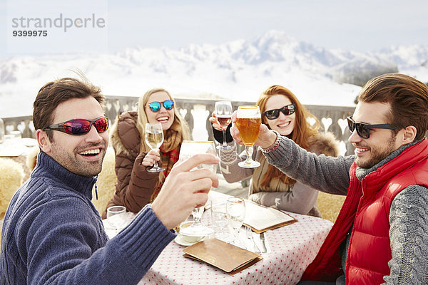 Freunde beim Feiern mit Getränken im Schnee