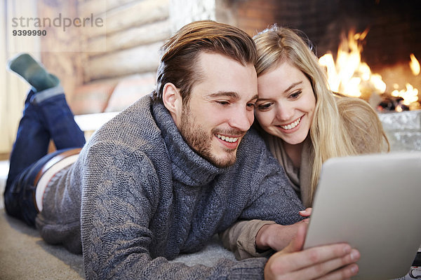 Paar mit digitalem Tablett über den Kamin zusammen