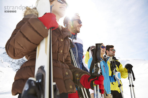 Freunde stehen mit Skiern auf dem Berggipfel