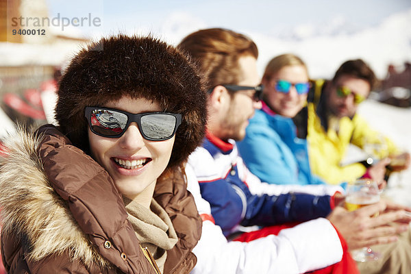 Frau sitzend mit Freunden im Schnee