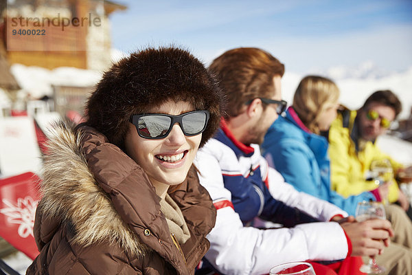 Frau sitzend mit Freunden im Schnee