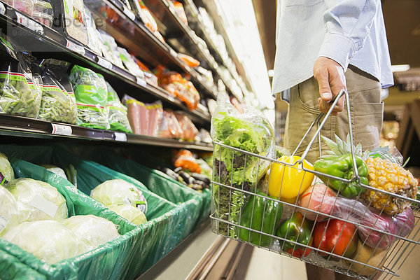 Mann mit vollem Einkaufskorb im Lebensmittelgeschäft