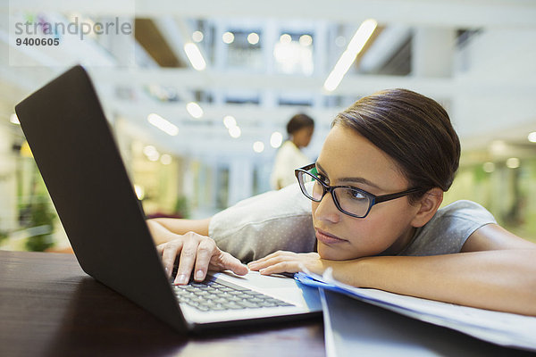 Geschäftsfrau entspannt mit Laptop im Bürogebäude