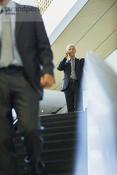 Geschäftsmann im Gespräch auf dem Handy auf der Rolltreppe im Büro