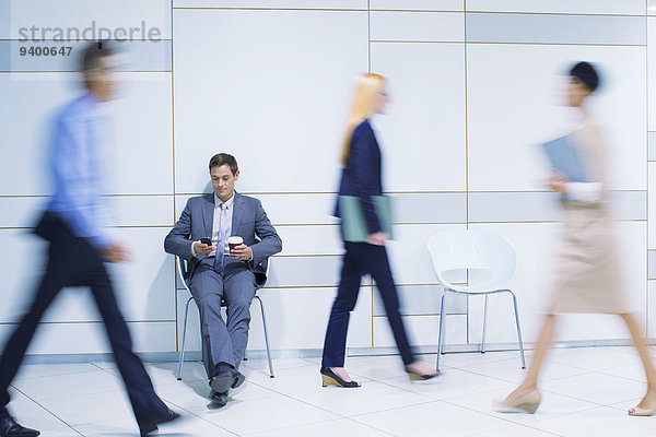Geschäftsmann sitzend mit Handy im Bürogebäude