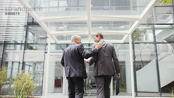 Geschäftsleute gehen gemeinsam in das Bürogebäude.