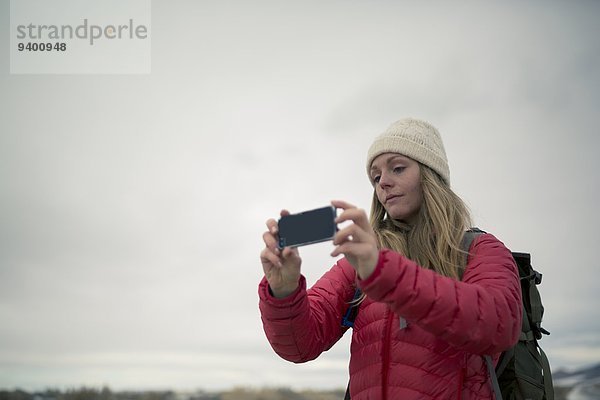 junge Frau junge Frauen Winter Kleidung Fotografie nehmen Smartphone