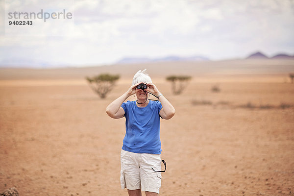 frontal Einzelperson eine Person grauhaarig Tag Freizeit Freizeitbekleidung Abenteuer Landschaft Schönheit 65-70 Jahre 65 bis 70 Jahre halten Wüste Querformat Fernglas Namibia Namib hindurchsehen Fokus auf den Vordergrund Fokus auf dem Vordergrund Idylle
