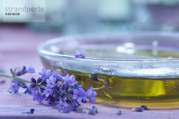 Lavendelblüten und Lavendelöl in einer Glasschale