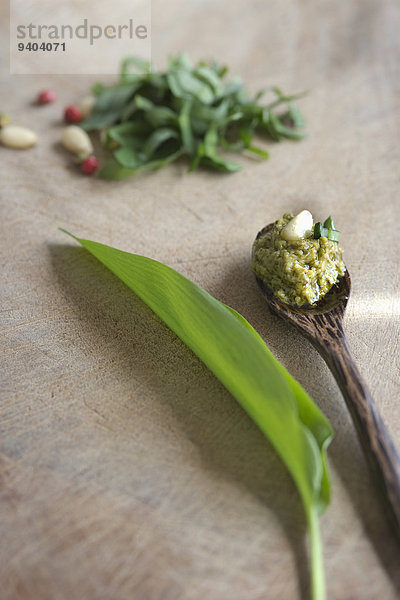 Bärlauch-Pesto und Pinienkern auf einem Holzlöffel neben Bärlauchblatt