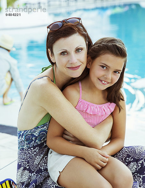 Porträt von Mutter und Tochter am Pool sitzend
