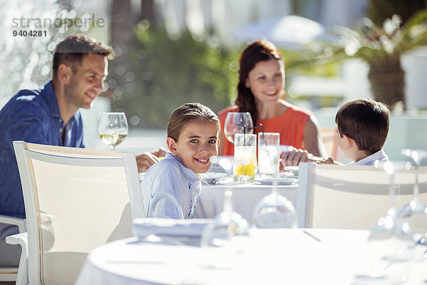 Familie mit zwei Kindern beim Abendessen im Resort im Freien