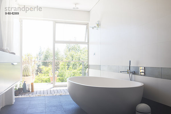 Modernes Badezimmer mit großer weißer Badewanne und Terrassentür