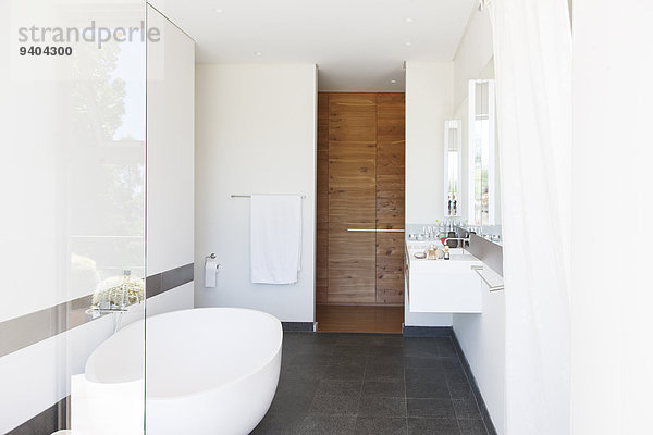 Moderne Badezimmerausstattung mit großer Badewanne und Holztür