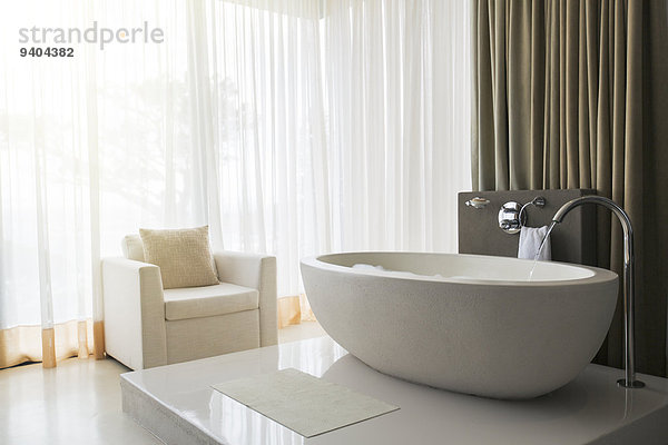 Blick auf modernes und luxuriöses Bad mit Badewanne und Sessel