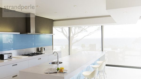 Moderne weiße Küche mit Kücheninsel und Hockern