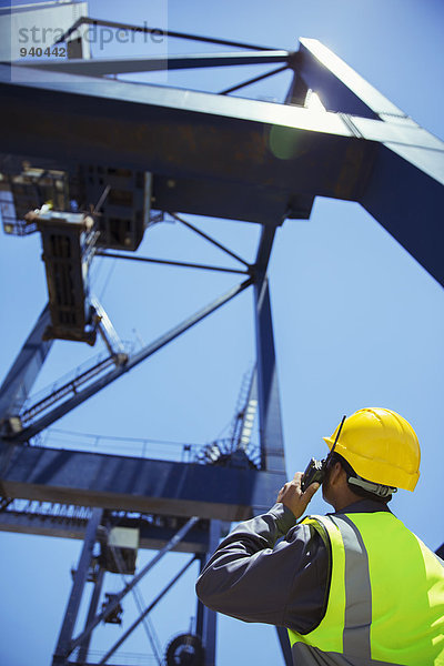 Niederwinkelansicht des Arbeiters mit dem Walkie-Talkie in der Nähe des Krans