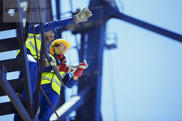 Niedriger Blickwinkel auf die Arbeiter  die auf dem Kran sprechen