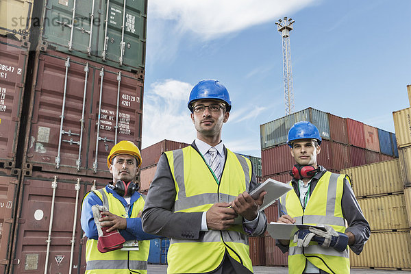 Geschäftsleute in Arbeitsschutzbekleidung in der Nähe von Frachtcontainern