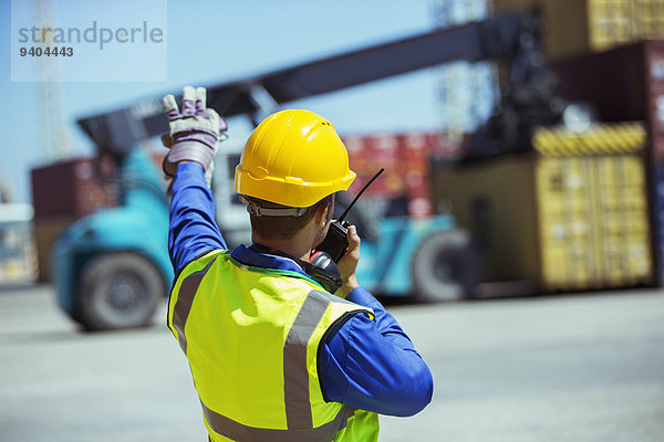 Arbeiter mit Walkie-Talkie in der Nähe von Frachtcontainern