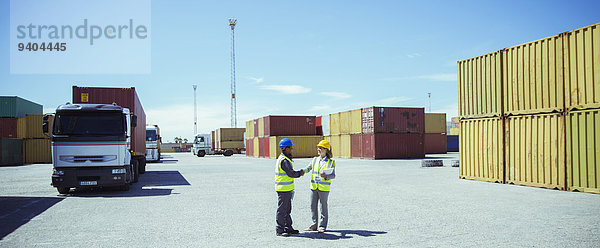 Arbeiter reden in der Nähe von Frachtcontainern