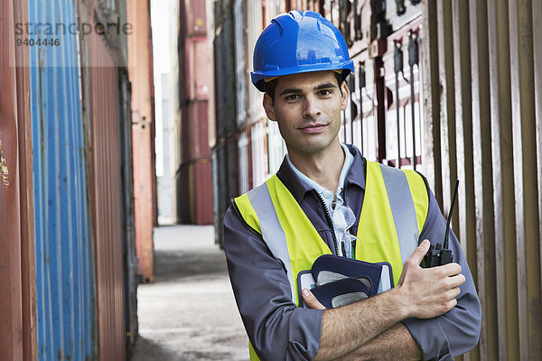 Arbeiter steht zwischen Frachtcontainern