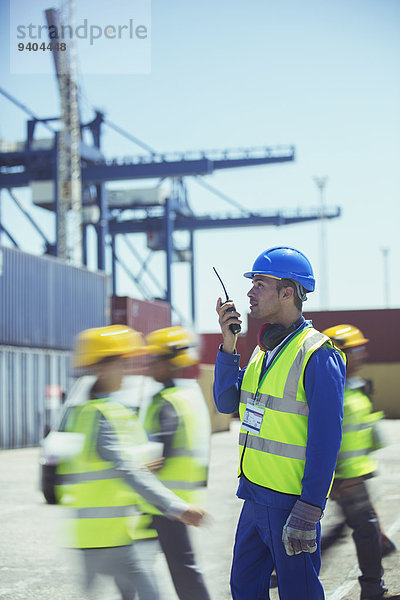 Arbeiter mit Walkie-Talkie in der Nähe von Frachtcontainern