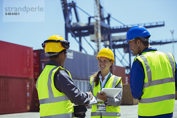 Geschäftsleute und Arbeiter sprechen in der Nähe von Frachtcontainern