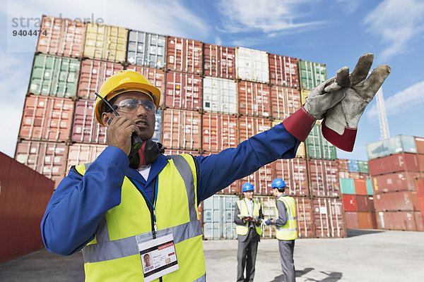 Arbeiter mit Walkie-Talkie in der Nähe von Frachtcontainern