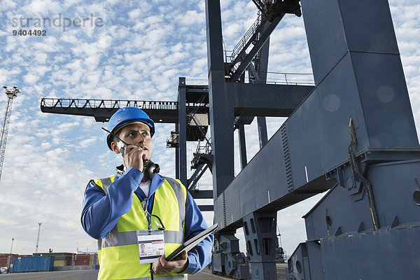 Arbeiter mit Walkie-Talkie unter dem Ladekran