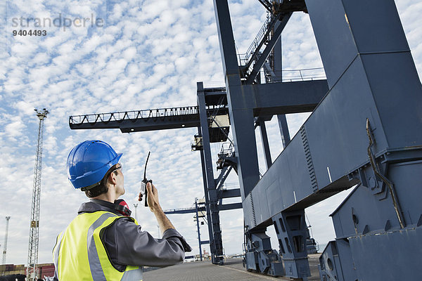 Arbeiter mit Walkie-Talkie unter dem Ladekran