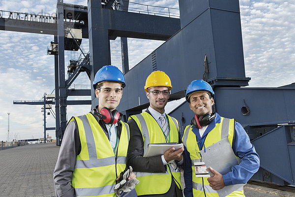 Arbeiter und Geschäftsleute lächeln in der Nähe von Ladekranen